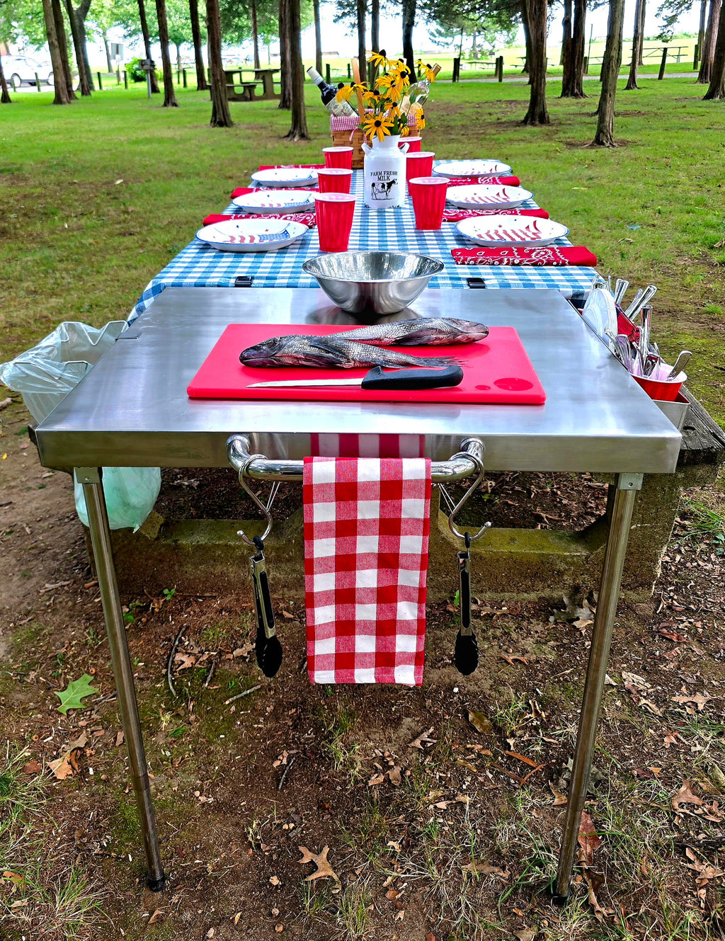 Fresh fish on a cutting board on The Big John Table, with a towel and tongs hanging from the side bar