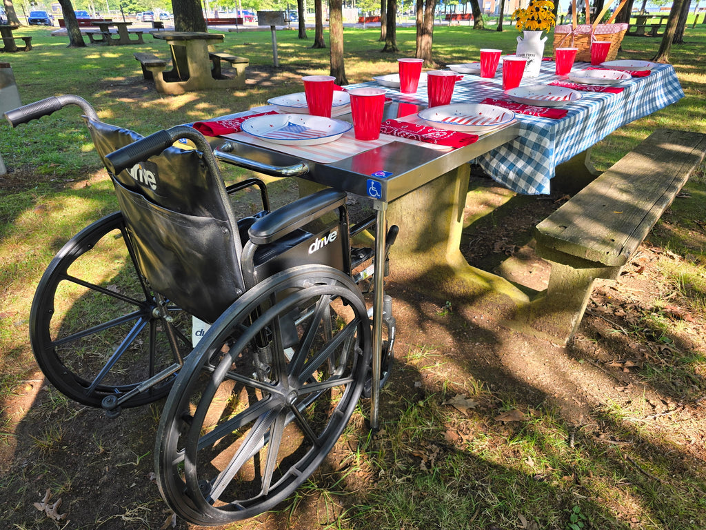 The Big John Table clamped to the end of a park picnic table, giving a wheelchair user room to pull right up to the table