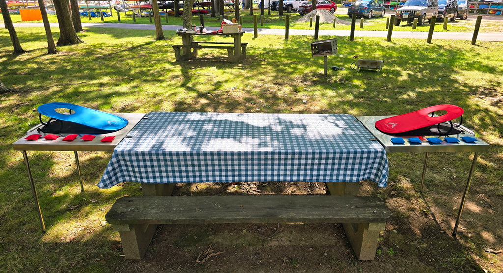 Two Big John Tables on the ends of a picnic table, each holding a lawn game board and bean bags